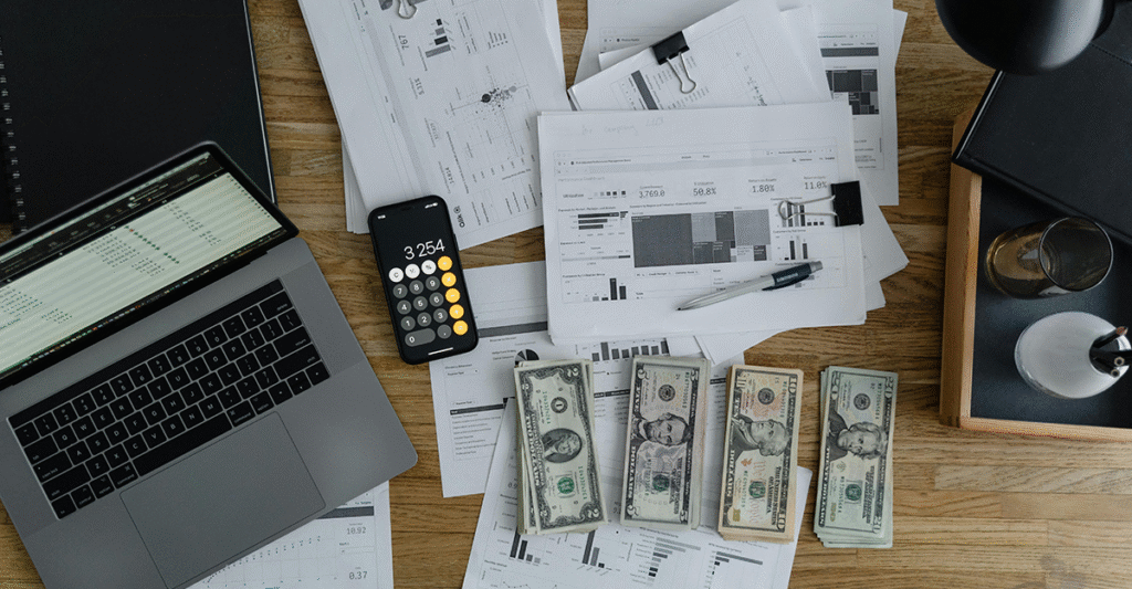 laptop computer with cash and reports on desk